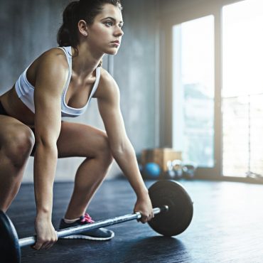 Your body deserves the best Shot of a sporty young woman working out with a barbell at the gym
